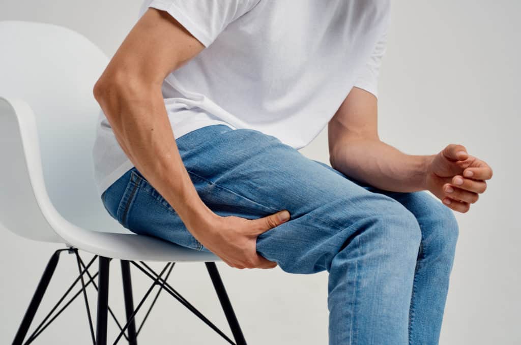 man holding his leg sitting on a chair