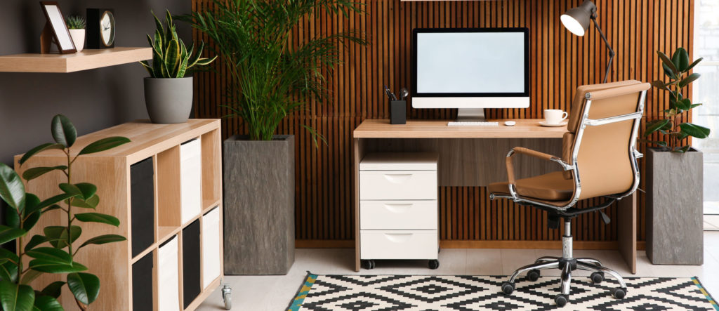 Comfortable workplace with computer near wooden wall in stylish