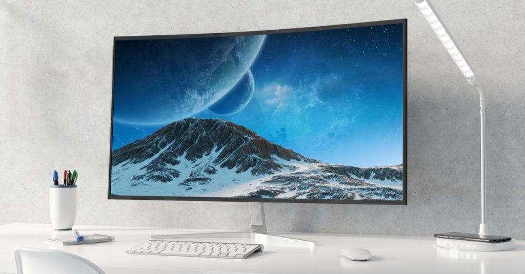 Curved monitor on white desktop and concrete interior