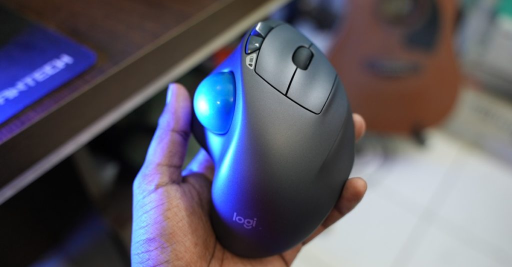 A Logitech M570 Trackball Mouse on a hand with blurred background