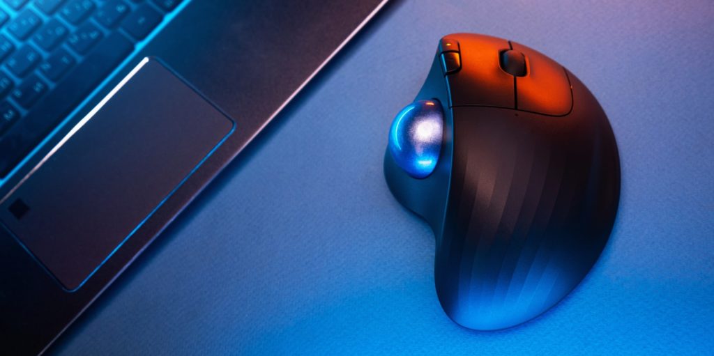 Wireless Trackball Computer mouse near the laptop on a blue background